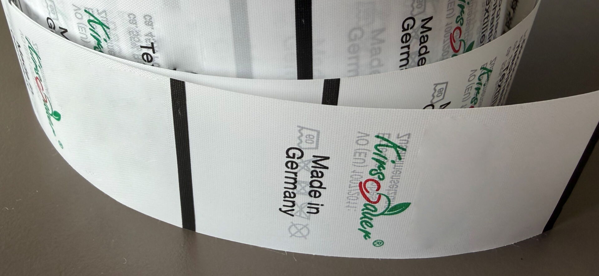 Verschiedene eingenähte Textiletiketten mit Waschsymbolen, Materialangaben und dem Kirschauer-Logo auf Reinigungstüchern